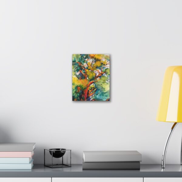 Art by Marina Zavalova. An "Patriarch" Watercolor - Canvas Stretched Print with vibrant autumn hues adorns a clean, modern wall, complementing the minimalist décor that includes neatly stacked books, a sleek black container, and a trendy yellow desk lamp.